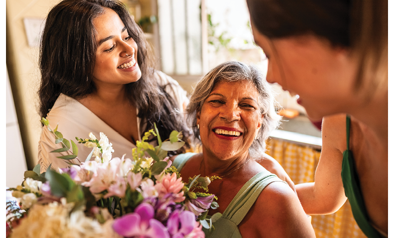 Young sisters giving flowers to grandmother at home